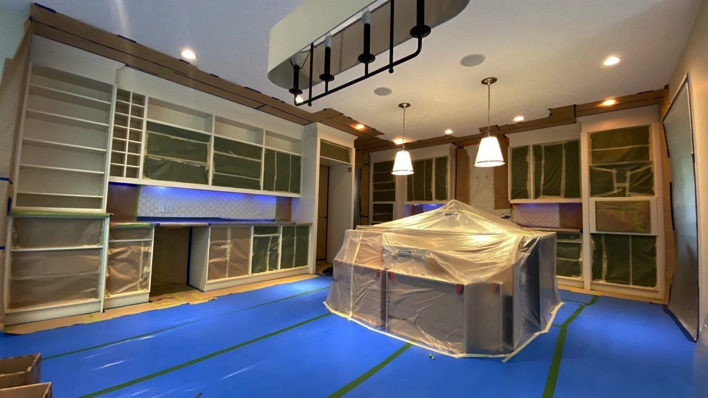 Kitchen protected during cabinet refinishing process with plastic sheeting