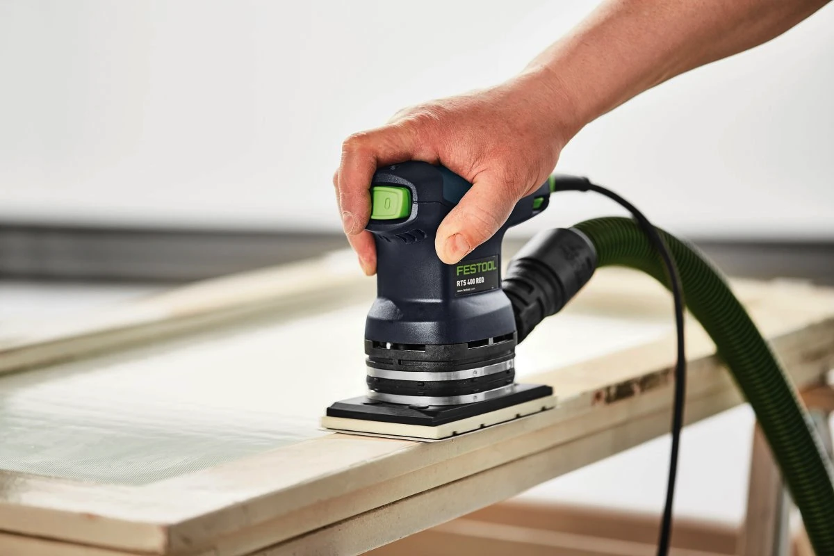 Professional using Festool dustless sanding system on cabinet surfaces