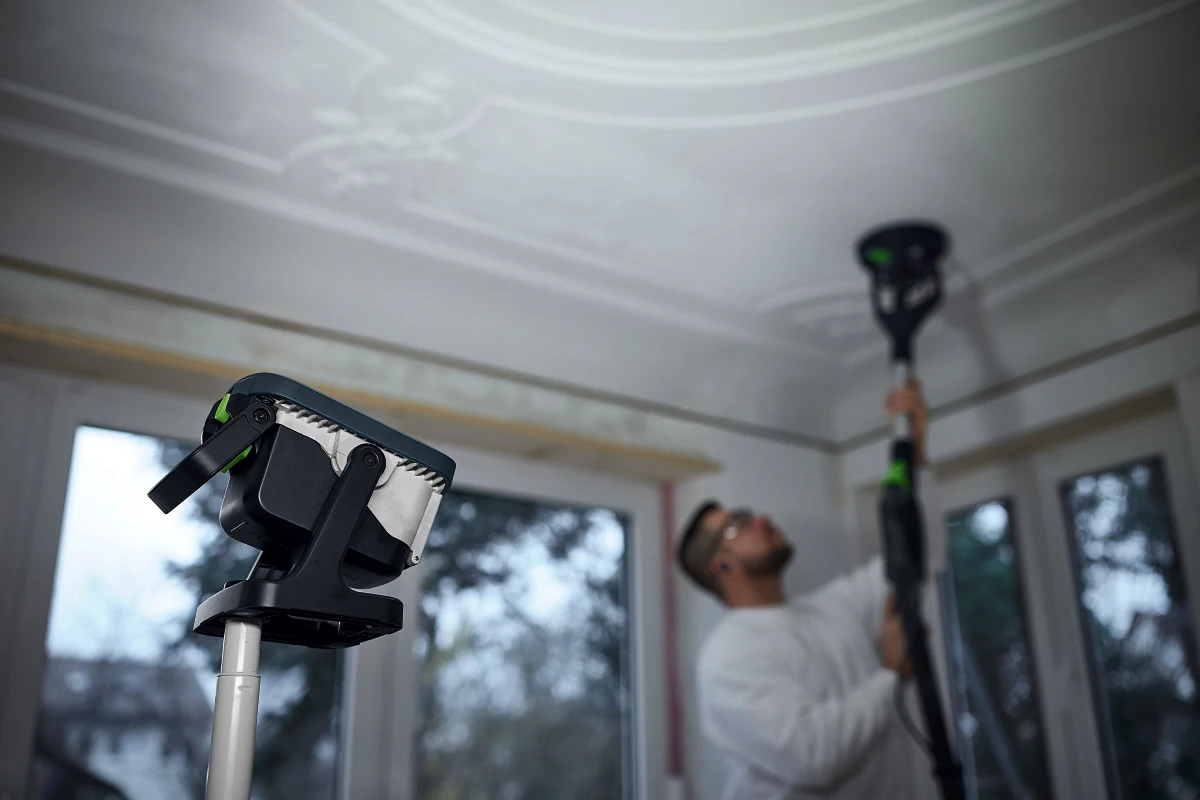 Professional using Festool dustless sanding system on ceiling trim